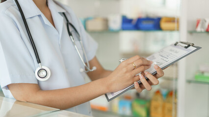 Medicine and health concept, Female pharmacist checking medicine on shelves to checklist in paper