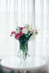 bouquet of flowers in a transparent vase on the table against the background of the window