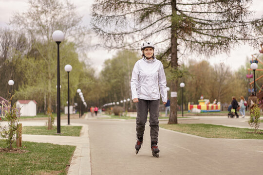 woman wearing a white helmet and white jacketon roller skates at a park