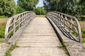 Munster, Germany, July 28, 2022: old and weathered wooden bridge across the river Ems for bicyclists and pedestrians