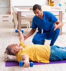 Obraz premium Young male doctor visiting old patient at home