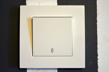 Building materials and accessories, white plastic switch and light switch located on the wall in the room.