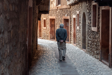 Fototapeta na wymiar Man from behind walks calmly through the streets of Albarracín.