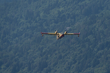 Fototapeta na wymiar flying seaplane taking up water in Caldonazzo lake during a fire