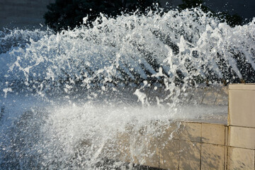 Bright splashes of clean water, jets, drops scatter from the fountain against the backdrop of the sun's rays.