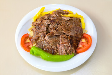 Turkish and Arabic Traditional Ramadan doner kebab with tasty tomato sauce and rice or turkish pilav in white plate on wood table background. ( , Iskender, ekmek arasi pilav ustu doner, doner durum )