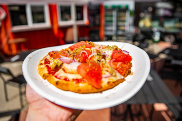 man holds plate with mini pita pizza in hands. Street food, fast food outdoor