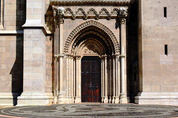 Beautiful oak wood church main door or gate of the Matthias church in Budapest. black forged steel decorative leaf pattern. carved beige stone entrance in neo gothic style. rich ornate sculpted arch