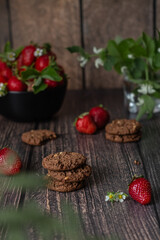 Chocolate cookies and ripe strawberries on a wooden table