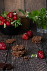 Fototapeta na wymiar Chocolate cookies and ripe strawberries on a wooden table