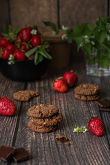 Obraz na płótnie Canvas Chocolate cookies and ripe strawberries on a wooden table