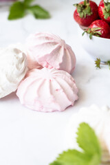 Fototapeta na wymiar Red and white marshmallows on a white background next to a bowl of strawberries