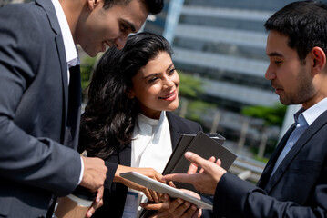 Asian business team in corporate wear meeting and talking outdoors in the city