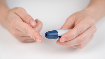 Caucasian woman doing a glucose test using a pen lancet. 