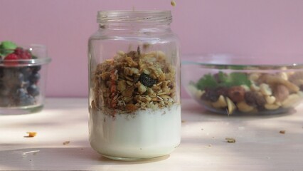 The girl prepares a delicious breakfast with yogurt, muesli, porridge and berries. environmentally friendly products. fresh fruits and berries. vitamins. jar granola