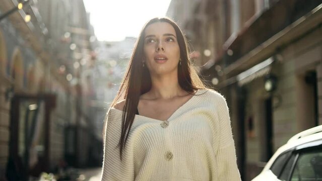 Portrait of stunning young woman walking down the street and looking ahead. Attractive woman in the city centre.