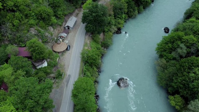 4k Above view of river, vegetation and road in countryside outdoors irrl. Aerial picture of emerald waters, green trees and asphalt road running through scenic area without anyone. Tourist uses drone