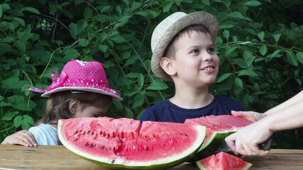Cute baby girl 3-4 year old and boy eating tasty watermelon over green nature background close up. Healthy lifestyle. Childhood. Summer time. happy satisfied children smiling