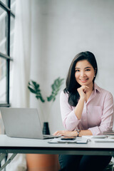 Asian businesswomn sitting working at the office. Looking at camera