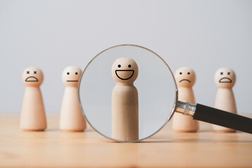 Smile face of wooden figure inside of magnifier glass among sad face for customer focus and relation management , excellent evaluation after client use product and service concept. - obrazy, fototapety, plakaty