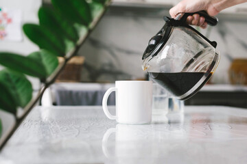Woman brewed coffee and pours it into a mug for breakfast.
