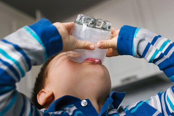 Child is drinking milk in the kitchen.