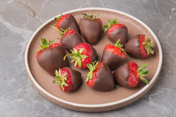 Top view on ceramic plate with dark chocolate covered strawberries. Dessert background.  Selective focus.