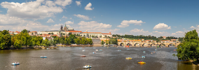 waterfront view across the river Vltava with pedal boats to Prague Castle and Charles Bridge,...