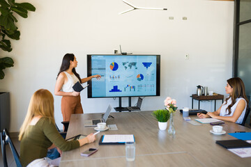 Latin female boss at a meeting talking with her work team