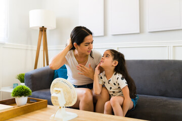 Mom and young kid feeling very hot during a heat wave at home