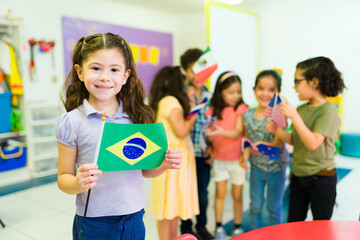 Cute preschool girl showing her Brazil's country flag - obrazy, fototapety, plakaty
