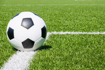 Fototapeta na wymiar Soccer ball on green synthetic artificial grass soccer sports field with white corner stripe line
