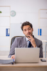 Young male employee sitting at workplace