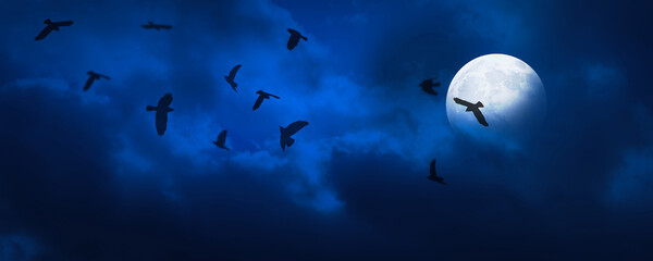 halloween background banner with crows around the shiny full moon at dark blue night sky