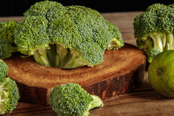 Raw green broccoli florets on a wooden board with ingredients. Close-up