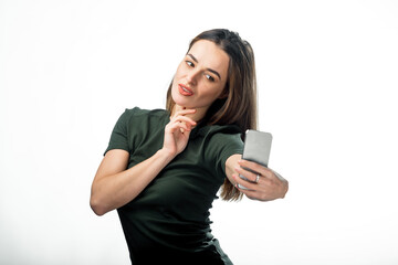 Model charming person with smartphone. Young pretty lady doing selfie in studio.