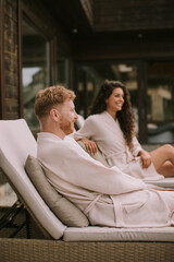 Young couple relaxing on beds  on the outdoor terrace