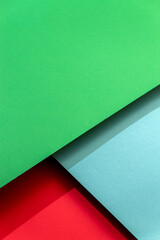 Abstract background with green, blue and red paper with hard shadows. Selective focus.