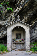 Fototapeta na wymiar Una poccola cappella sotto uno sperone di roccia lungo la Via del Volto Santo, cammino che parte da Pontremoli e arriva a Lucca