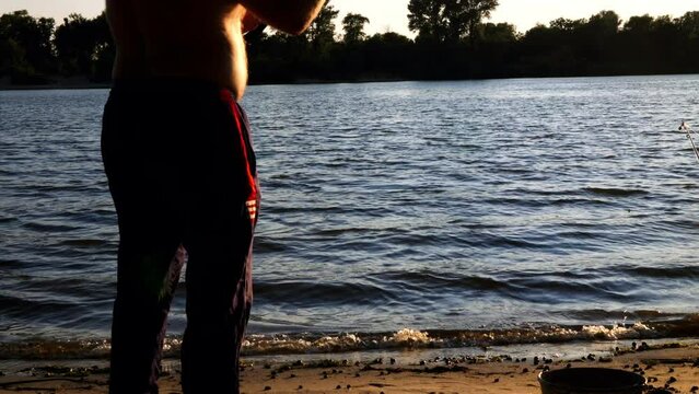 Fisherman loser. The angler throws his rod into the river, the fishing line breaks, the hook with the sinker sinks in the water. Fishing on the lake in nature. The fisherman throws up his hands. Funny