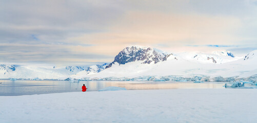 Antarktis Tourist in rotem Parka vor antarktischer Eisberg Landschaft bei Portal Point welches am Zugang zu Charlotte Bay auf der Reclus Halbinsel, an der Westküste von Graham Land liegt