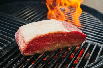 Barbecue dry aged wagyu roast beef steak grilled as close-up on a charcoal grill with fire and smoke