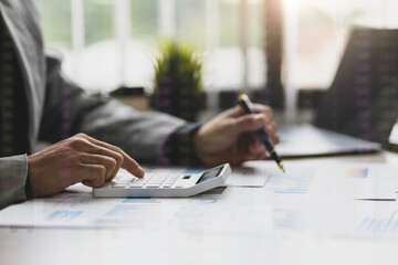 Business people use calculator to analyze financial charts in business reports.