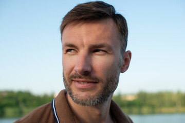 One man with stubble looks to the side, close-up.