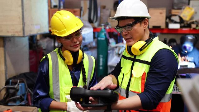Female and male industrial factory engineer and technician worker wearing safety vest and hard hat helmet. Metal lathe industrial manufacturing factory. Opertor automation robot welding machine