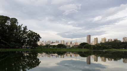 Fototapeta na wymiar View of Ibirapuera Park, the first metropolitan park in São Paulo, Brazil, and one of the most visited parks in South America. In the background part of the city’s skyline reflected in a lagoon