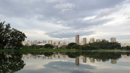 View of Ibirapuera Park, the first metropolitan park in S&atilde;o Paulo, Brazil, and one of the most visited parks in South America. In the background part of the city&rsquo;s skyline reflected in a lagoon