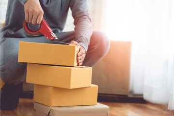 Detail of packing cardboard boxes while moving house. Young man packing box, indoors young male warehouse worker packing boxes for shipment. 