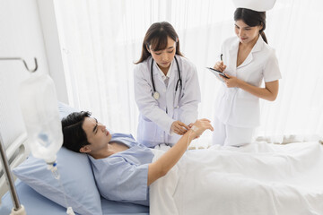 Obraz premium Female doctor and nurse visiting checking recover male patient at hospital