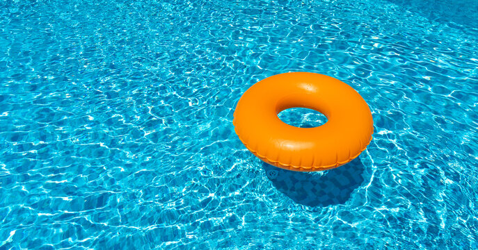 Orange ring floating in blue swimming pool. Inflatable ring, rest concept